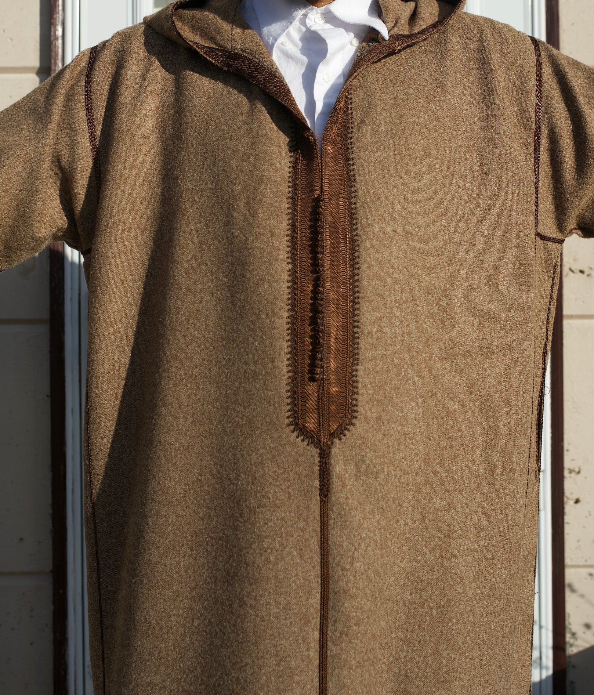 Brown hooded garment with a zipper on a mannequin against a neutral background
