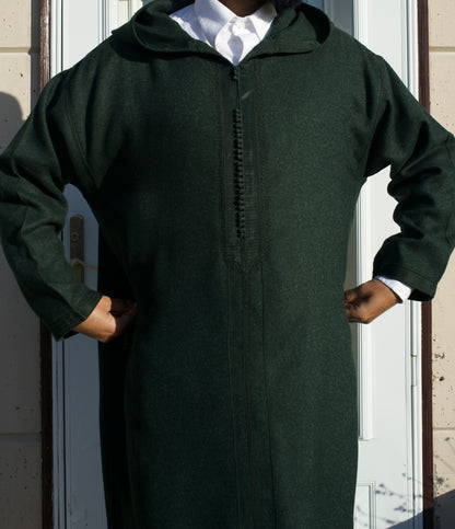 Person wearing a long dark green robe with a hood in front of a white door.