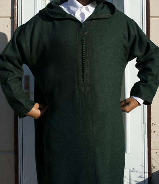 Person wearing a long dark green robe with a hood in front of a white door.