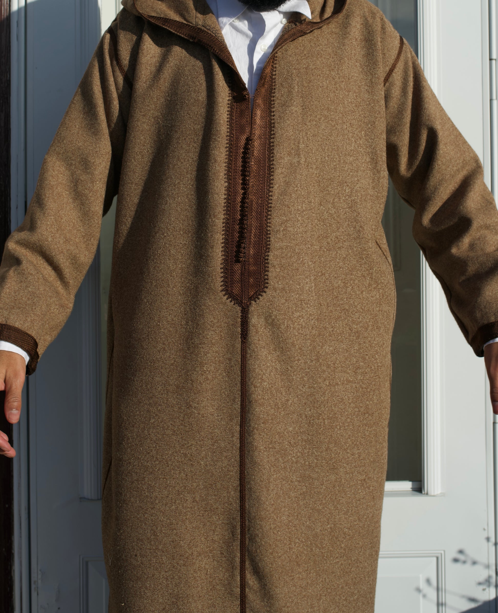 Brown hooded garment worn by a person against a neutral background