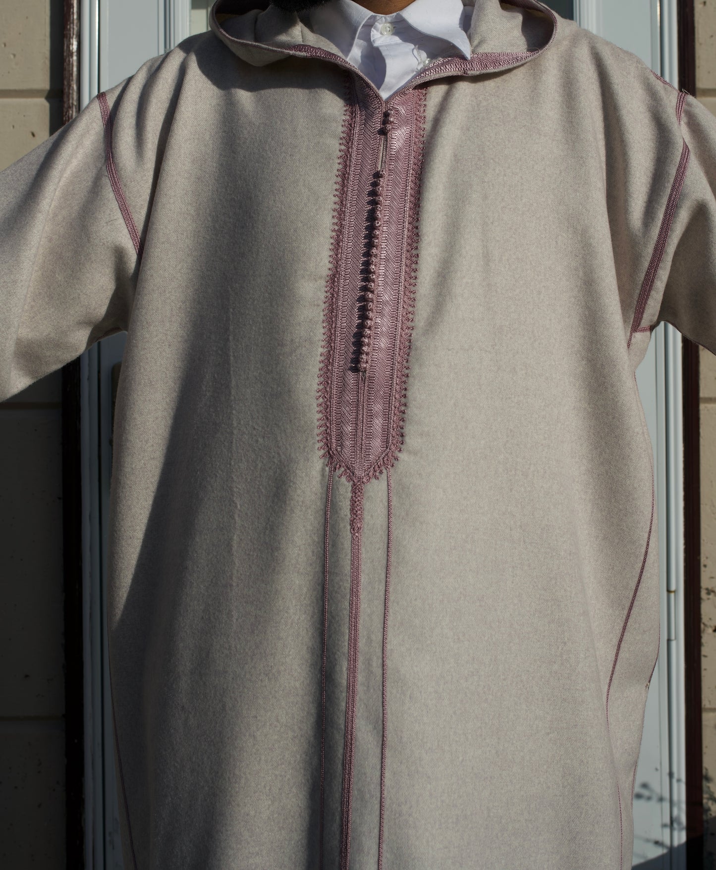 Beige traditional garment with embroidered details on a mannequin against a neutral background