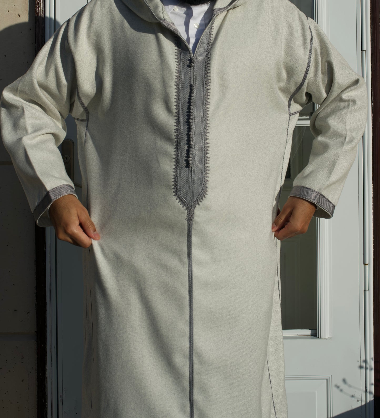 Person wearing a light gray traditional outfit with a zipper detail, standing against a neutral background.
