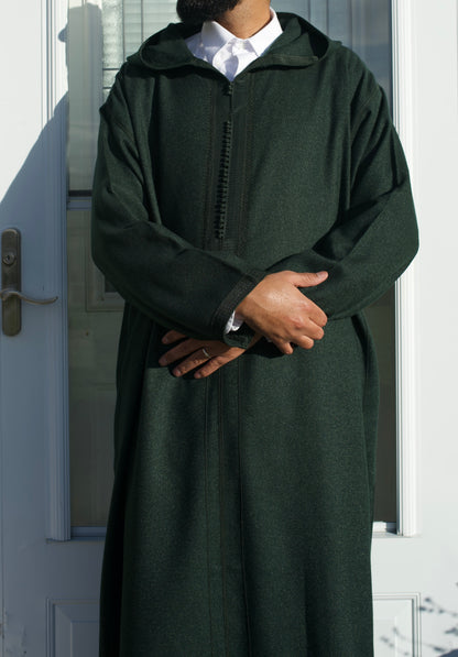 Person wearing a dark green hooded garment in front of a door.