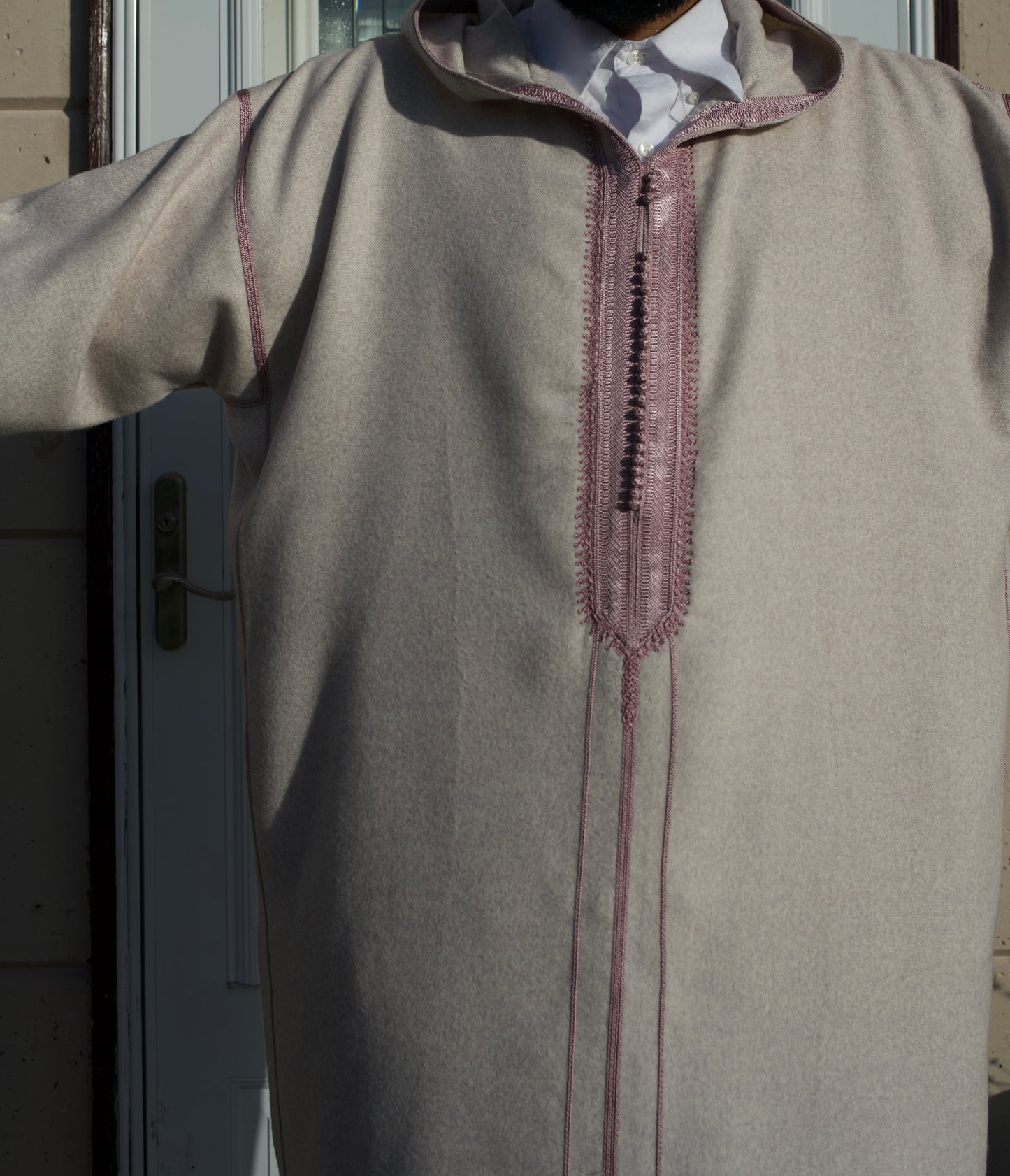 Beige long-sleeve shirt with decorative stitching on a plain background