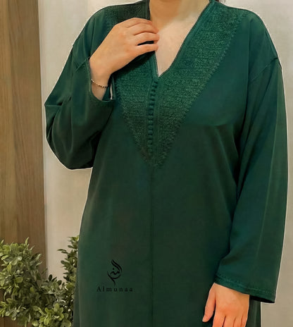 Green dress with intricate neckline design, worn by a person, against a neutral background.