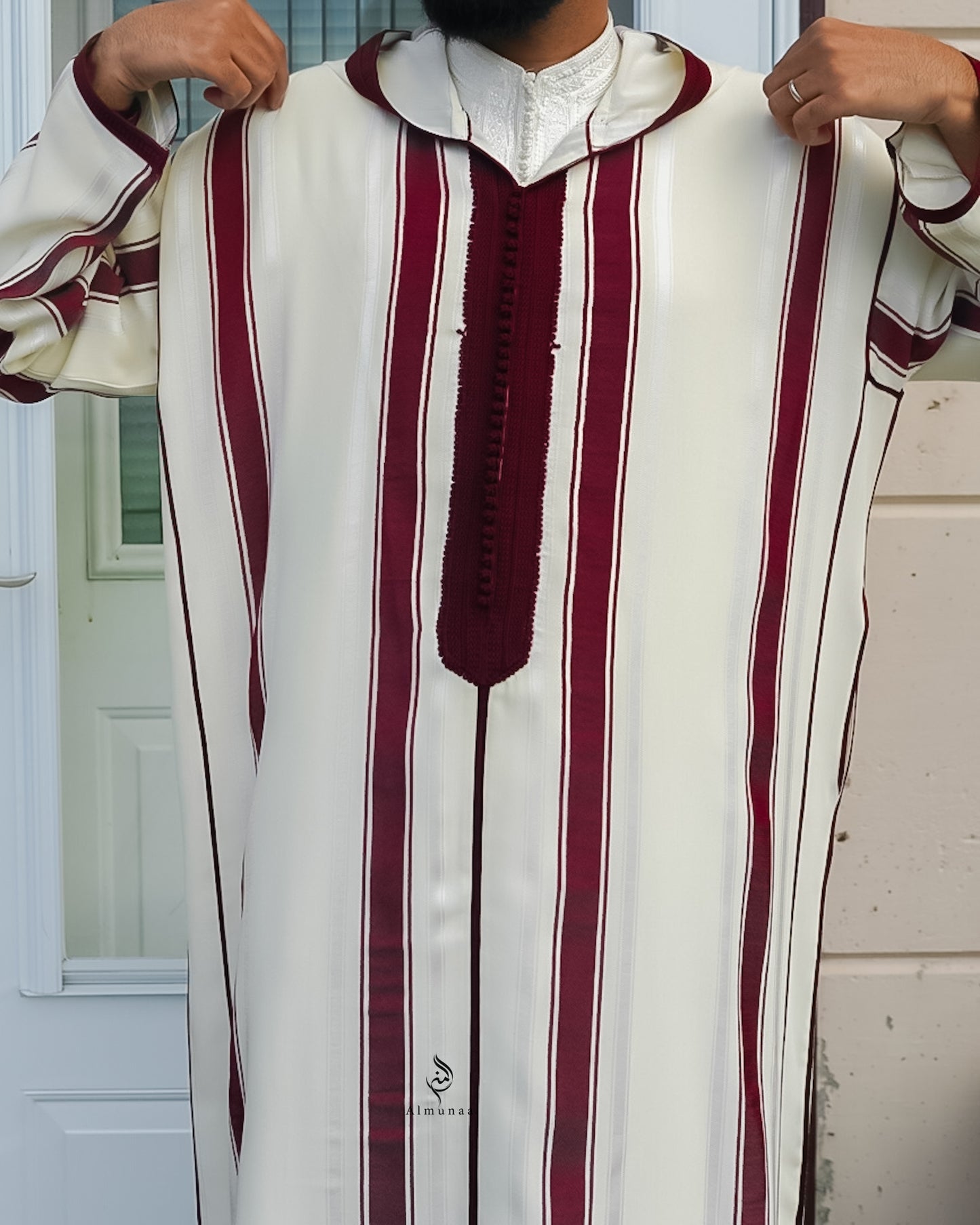 White garment with red stripes held by a person against a neutral background