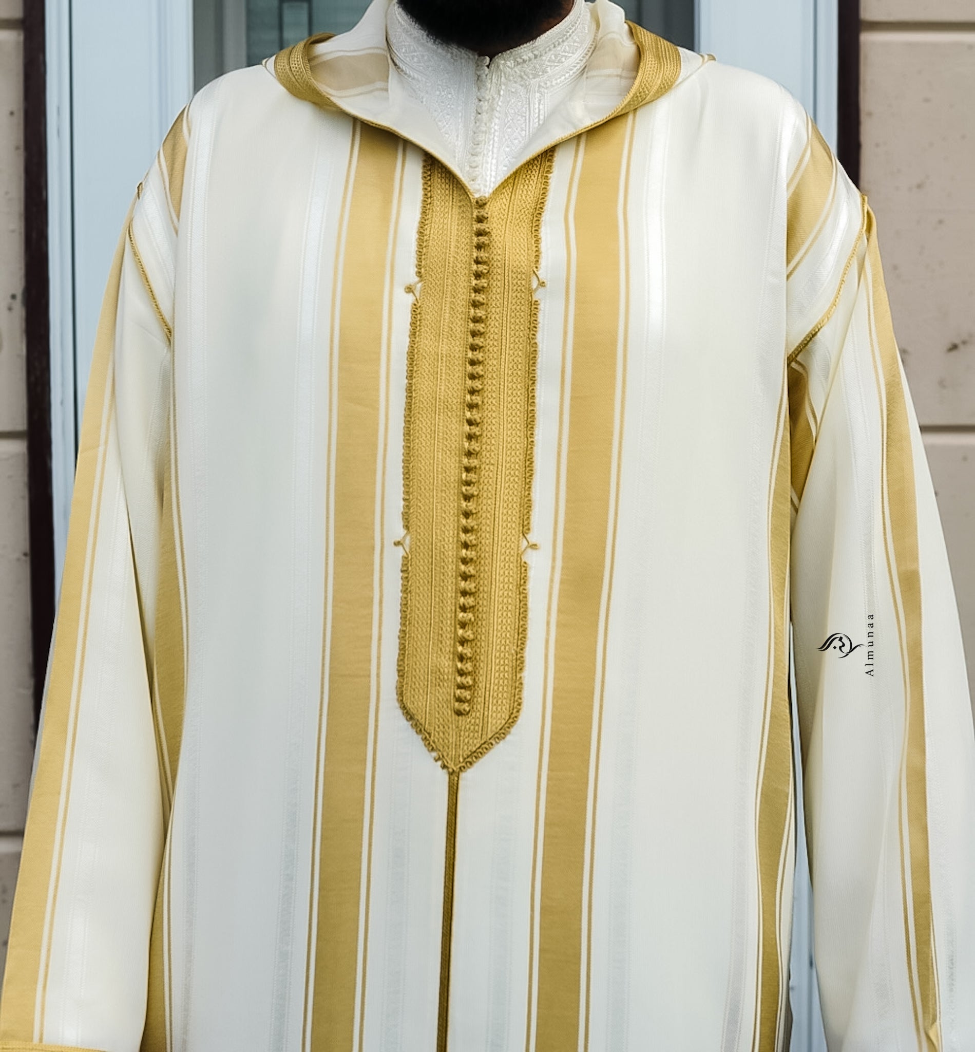 White garment with gold stripes and a zipper, featuring the brand 'Almanar'.